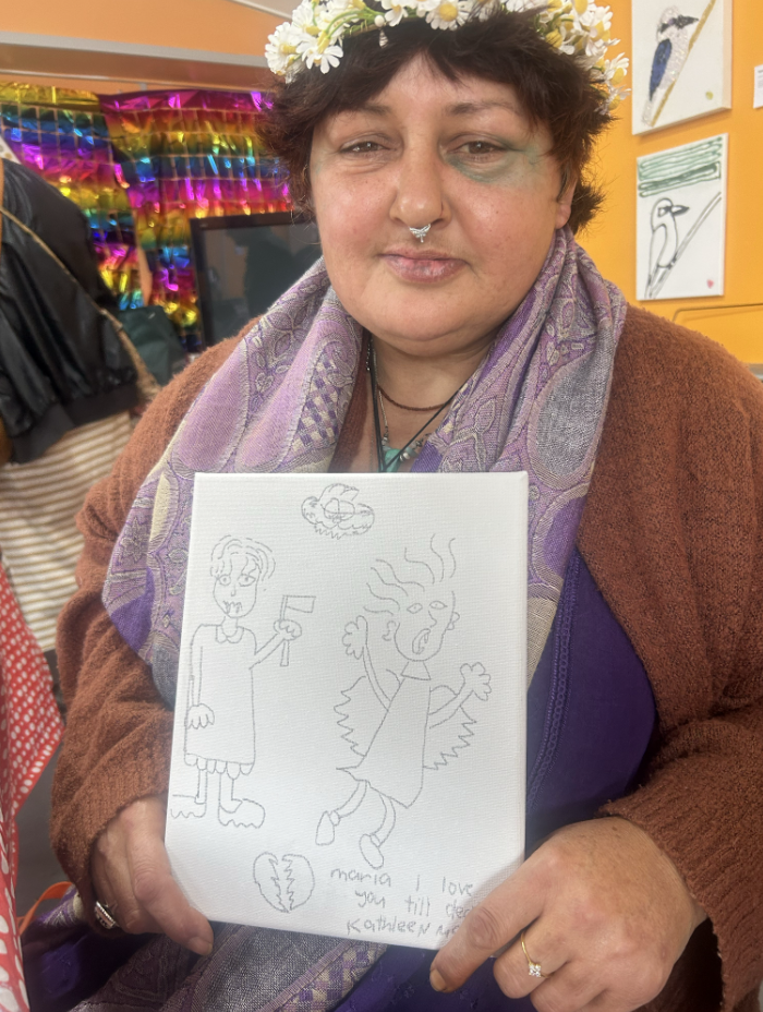 Kathleen holding up a drawing she made on canvas